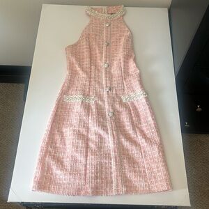 Mid length platted pink dress with pearls around the neck and pocket area